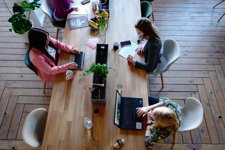 Three Woman Sitting on White Chair in Front of Table in a co-working space in Hong Kong
