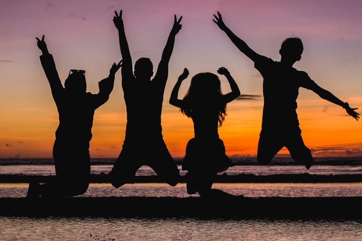 silhouette figures jumping at beach