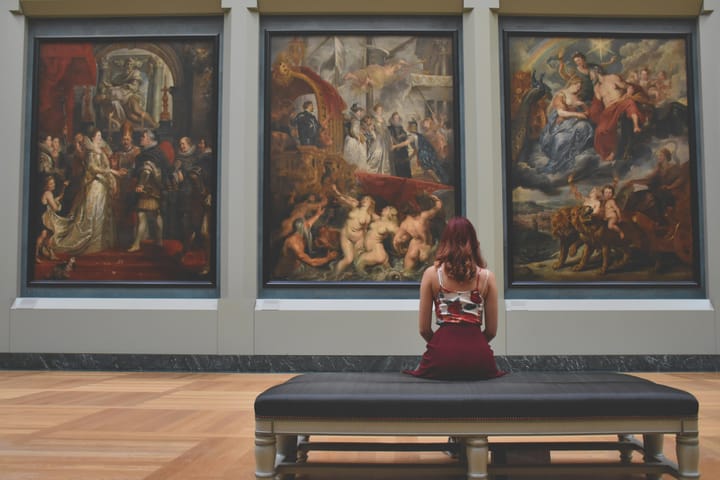 woman sitting on bench in front of paintings