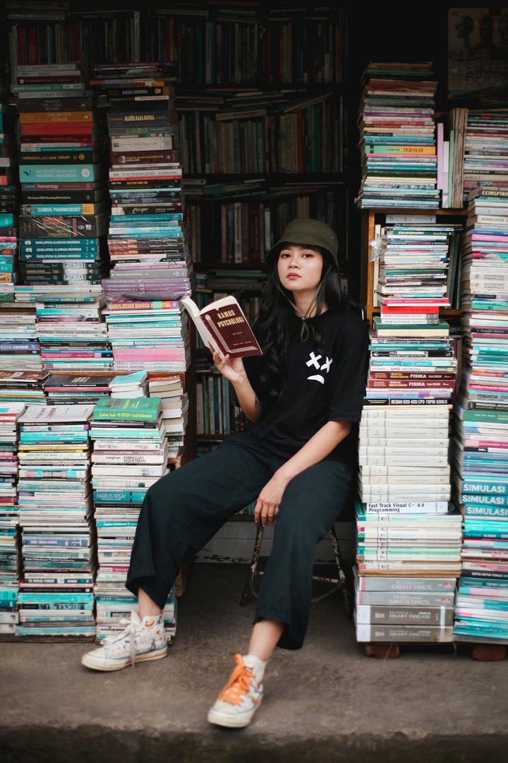 woman in black crew neck t shirt sitting on books