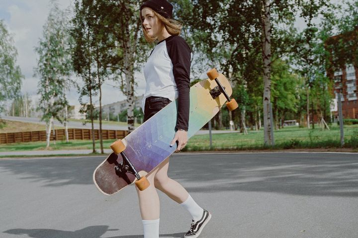 woman in white and black long sleeve shirt holding a longboard