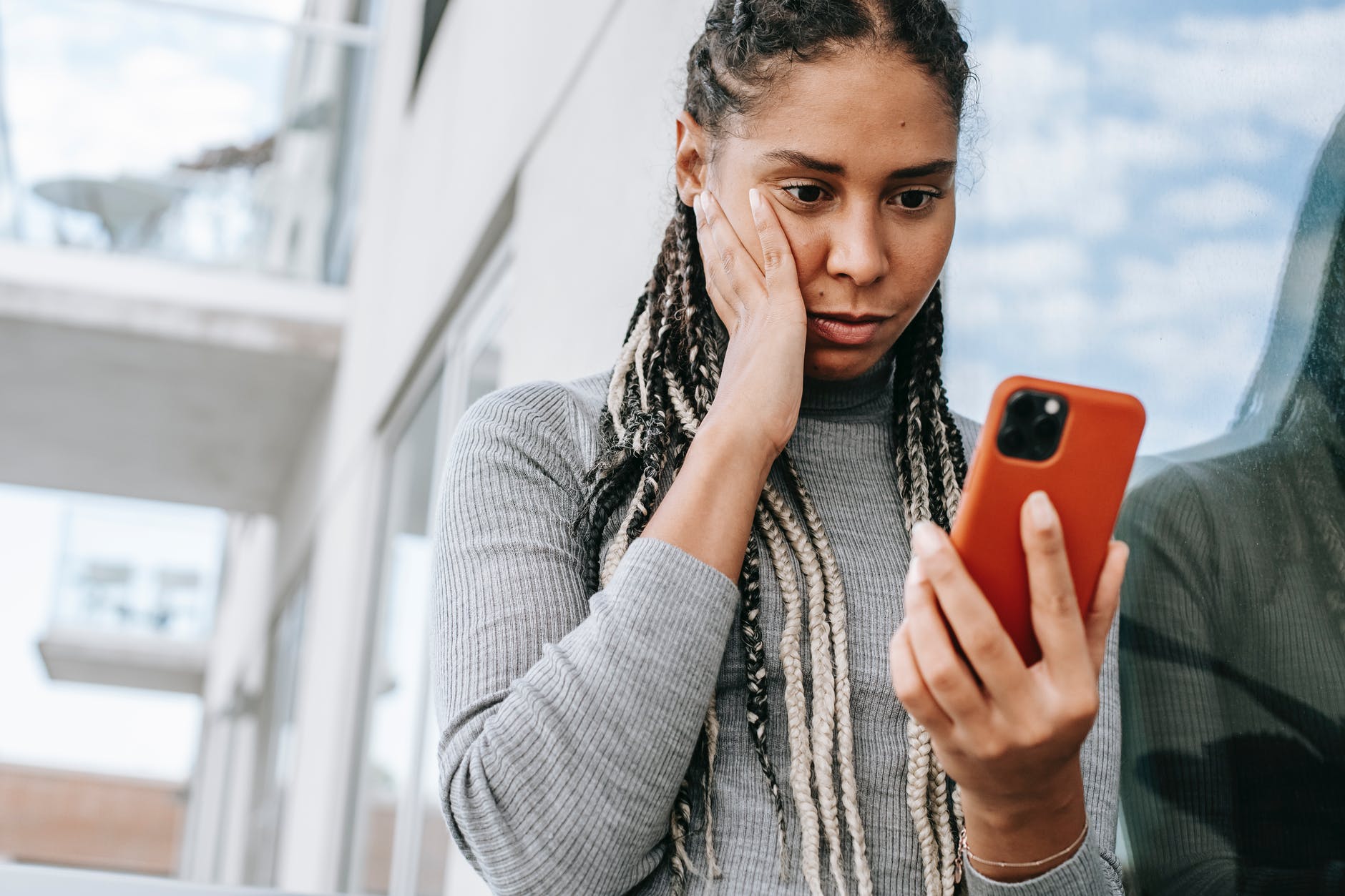 crop concerned black woman using smartphone on street